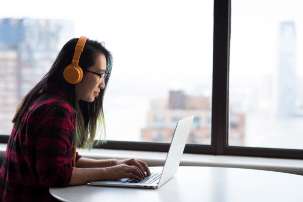How to Become a Zoom Power User - Image of a woman wearing headphones and using a laptop