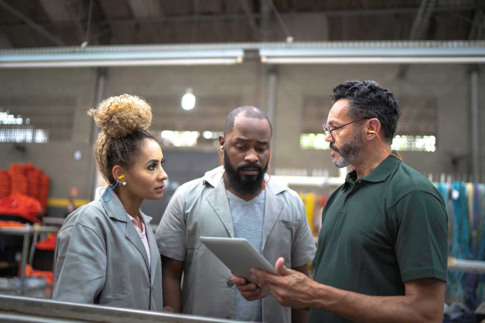 Manufacturing workers reviewing information on a tablet.